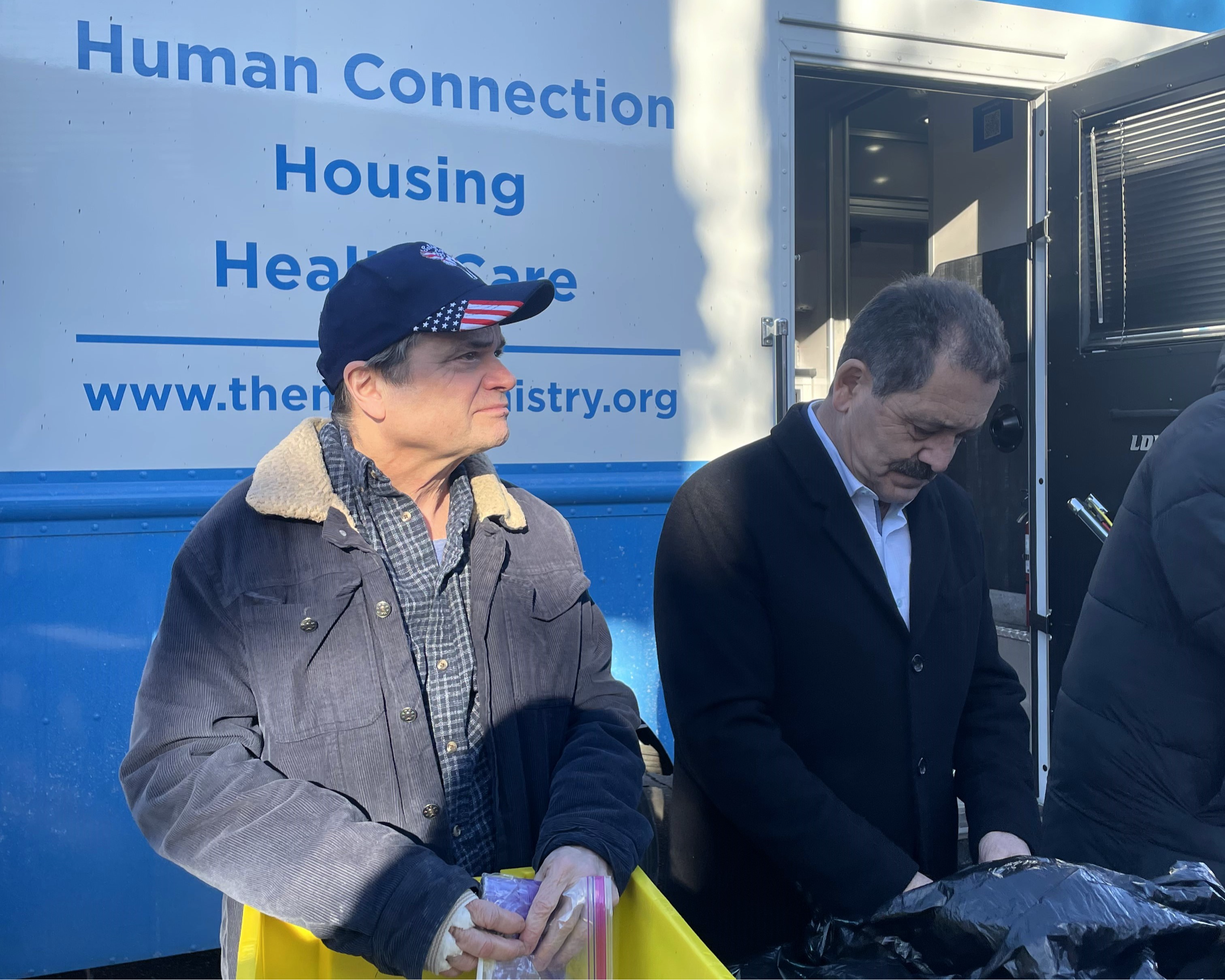 Two men, Reps. Mike Quigley and Chuy Garcia, help distribute toiletries