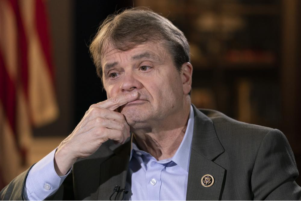 Rep Quigley sits in a dim room, with his hand on his face, looking thoughtful