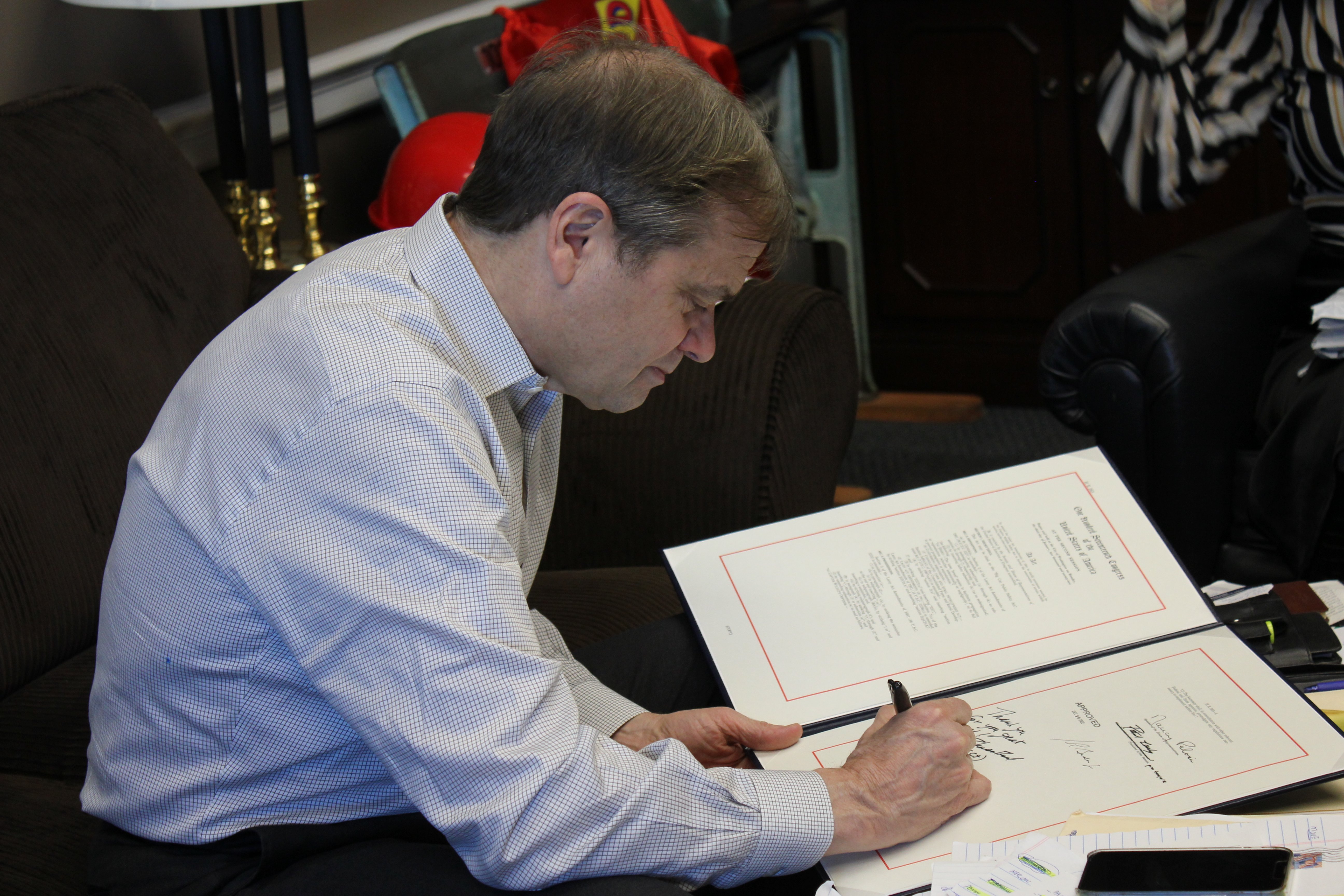 Rep Quigley signs a large piece of paper.