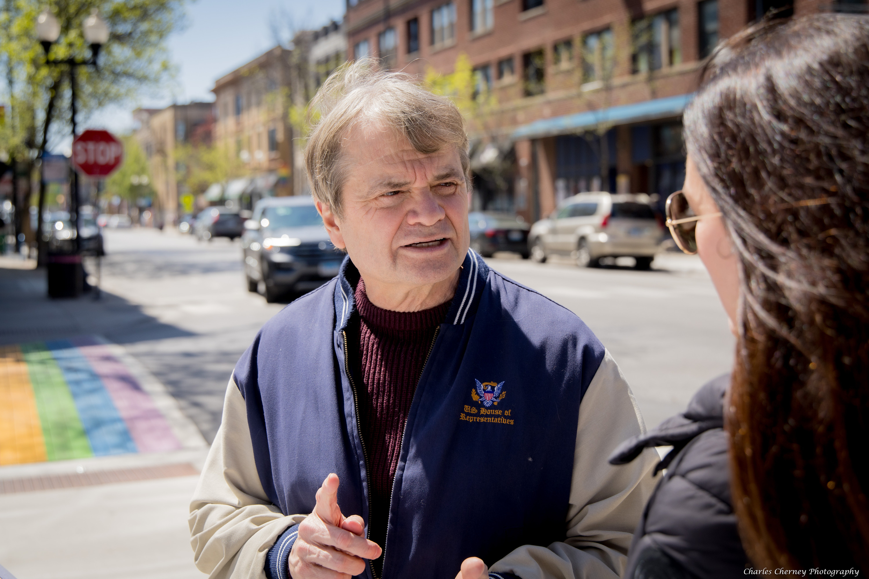 Rep Mike Quigley speaks to a woman on the streets of Northalsted. Behind him are the painted pride crosswalks of Northalsted.